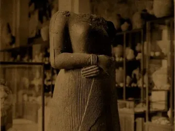 Headless stone statue of Napir-Asu with hands clasped across the midsection and a pleated long garment.