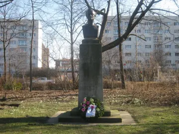 Richard Wagner bust on a tall stone pedestal in a park, with a floral wreath at the base.