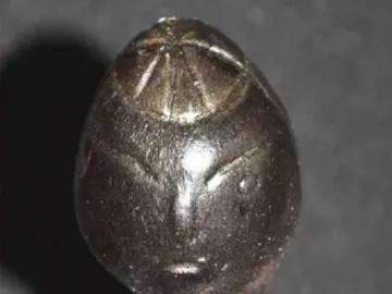 Close-up of the Venus of Langenzersdorf showing the elongated head, incised facial lines, and slender neck.