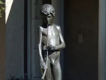 Spirit of Spanish Music bronze sculpture of a barefoot boy playing a long wind instrument on a fountain base