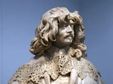 Marble bust of Thomas Baker with long wavy hair, a mustache, and an ornate lace collar.