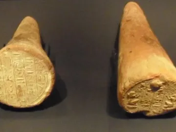 Two ancient Egyptian funerary cones with pressed hieroglyphic inscriptions on the flat ends.