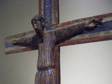 Batlló Majesty, a painted wooden crucifix sculpture with a robed figure, outstretched arms, and red and blue decorative patterns