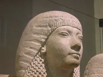 Detail of the Horemheb and Amenia limestone statue showing the husband’s head and upper torso in profile, with a second figure partly visible.