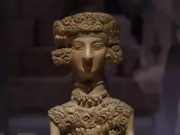 Lady of Ibiza terracotta statuette with an elongated neck, stylized face, and ornate patterned headpiece.