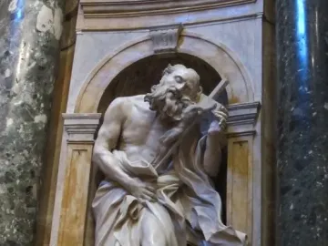 Saint Jerome sculpture by Gian Lorenzo Bernini, showing a bearded figure in flowing robes holding a cross and standing with one foot on a lion\'s head.