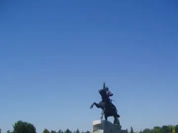 Suvorov Monument, a dark equestrian statue on a light stone pedestal above a grassy mound with a person walking nearby.
