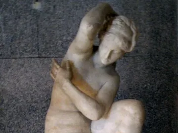 Crouching Venus marble sculpture of a nude female figure in a crouching pose on a base.