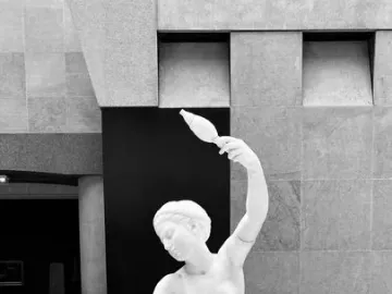 Jeune fille de Mégare, a white marble sculpture of a seated young woman holding a spindle and distaff