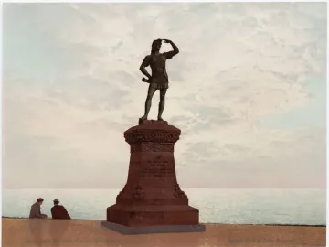 Leif, the Discoverer statue on an ornate pedestal overlooking the water, with two people seated nearby.
