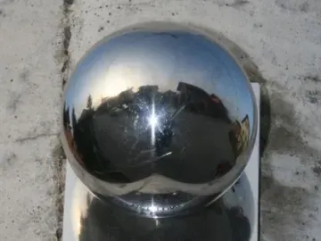 Neptune plaque beside a shiny metallic sphere mounted on a grey wall.