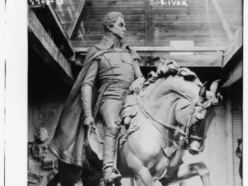 Black and white photograph of the Simón Bolívar equestrian statue with a worker standing beside its base.