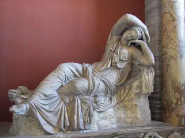 Sleeping Ariadne reclining in white marble with draped fabric and one arm raised over her head.