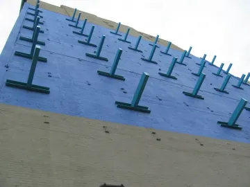 The Wall at Gateway to Soho, showing a blue upper section with teal T-shaped protrusions over a tan lower wall.
