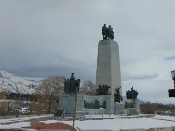 This Is the Place Monument with bronze pioneer figures, horses, and wagons at its base