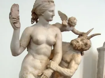 Aphrodite, Pan and Eros sculpture showing a nude woman holding a sandal above her head as Pan grasps her arm and a winged child presses down on Pan.