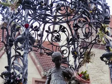 Gänseliesel Fountain bronze statue of a girl holding a goose and a basket of flowers beneath an ornate canopy.