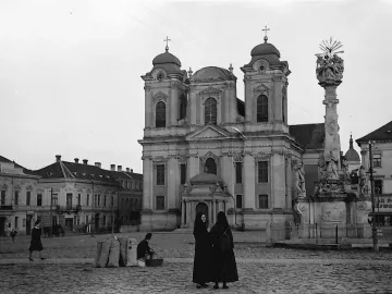 Holy Trinity Monument standing in a cobbled town square with a church in the background.