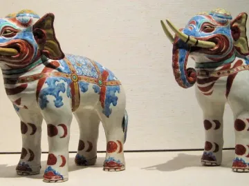 Pair of Kakiemon porcelain elephant figurines decorated in white, blue, red, and gold with yellow tusks.
