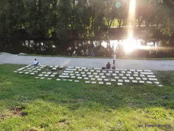 Keyboard Monument made of stone blocks along a grassy riverbank with people among the keys
