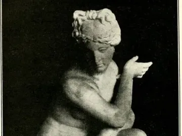 Crouching Venus statue in a crouching pose on a carved pedestal.