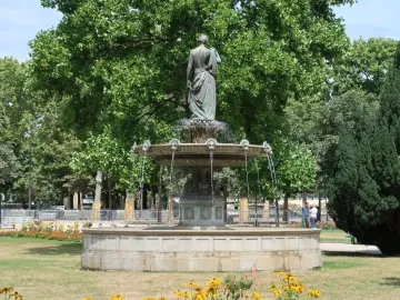 Diana Fountain seen from behind beside a stone basin and circular pool, surrounded by trees and greenery.