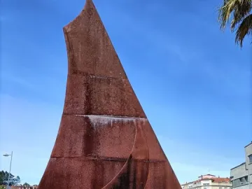 Dorna, a large abstract reddish-brown metal sculpture in an outdoor plaza with landscaping and city buildings behind it.
