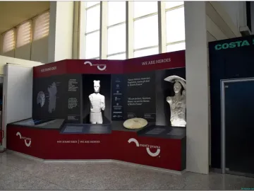 Two Giants of Mont\'e Prama statues displayed in a red and black exhibition stand.