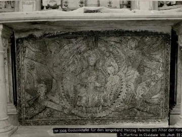 Carved stone panel from the Rachis Altar with a haloed central figure, smaller saints, angels, and ornate foliage reliefs.