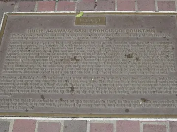 A metal plaque with engraved text rests in a red-brick paved surface.