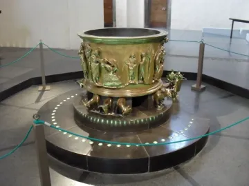 Baptismal font at St Bartholomew\'s Church with bronze relief figures and animal supports.
