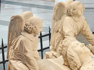 Detail of the Tomb of Francis II showing a recumbent figure’s head resting on a patterned pillow, with kneeling angels supporting it.