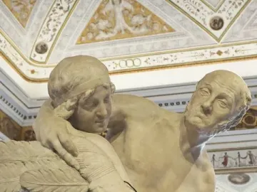 Daedalus and Icarus marble sculpture detail showing an older man embracing a younger figure with feathered wings.