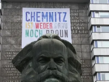Karl Marx Monument in Chemnitz framed by two banners reading \