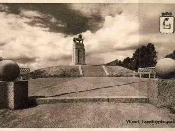 Lion statue atop a tall stepped monument in Monrepos, with spherical sculptures in the foreground.