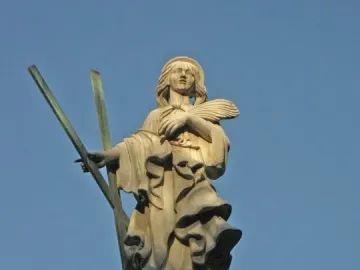 Stone statue of Santa Eulàlia with a halo, holding crossed staves and palm fronds on an ornate base.