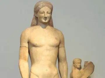 Kouros marble statue of a nude male figure with long hair, missing the right forearm, with a winged sphinx sculpture behind it.