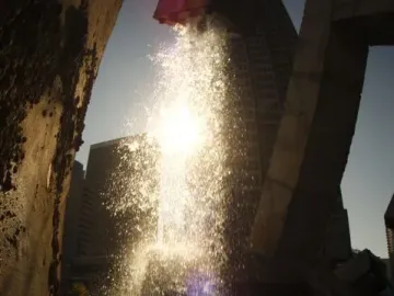 Vaillancourt Fountain with water splashing brightly in the sun between dark concrete structures.