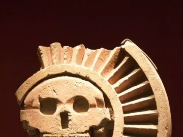 Disk of Mictlāntēcutli stone carving with a skull-like face and ribbed fan-shaped detail