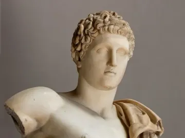 Hermes Belvedere marble sculpture with curly hair, a draped shoulder cloth, and a broken left arm.
