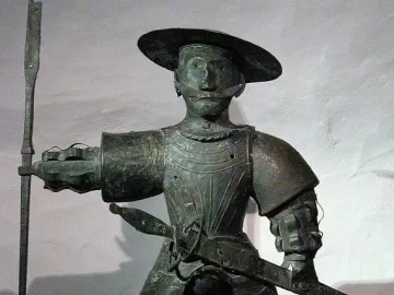 Old Thomas statue of a man in armor with a wide-brimmed hat, mustache, spear, and sword
