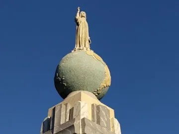 Divino Salvador del Mundo statue of Jesus standing on a globe against a blue sky