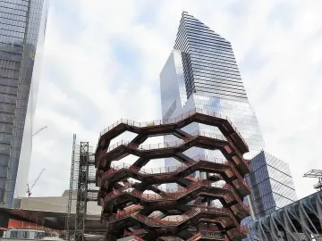 The Vessel rises among glass skyscrapers, with a chain-link fence and Gate 14 sign in the foreground.