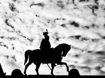 Silhouetted rider on the Victor Emmanuel II Equestrian Statue against a cloudy sky.
