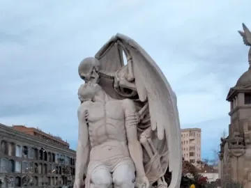 The Kiss of Death sculpture showing a winged skeletal figure embracing a kneeling man in a cemetery.