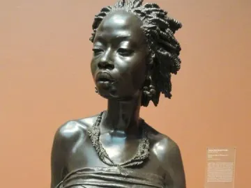 The Nubian Woman bronze bust with braided hair, earrings, and a draped garment.
