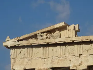 Parthenon pediment sculptures showing a reclining figure and a horse head against the sky.