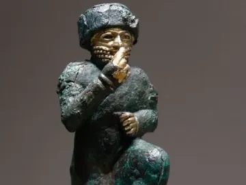 Worshipper of Larsa kneeling figure with a raised hand and gold details on an oxidized green surface.