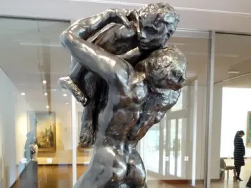 I Am Beautiful, a bronze sculpture showing a muscular male figure carrying a smaller figure on his back and shoulders.