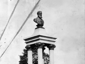 Maitland Brown Memorial stone monument topped with a bust and relief panels on a grassy site